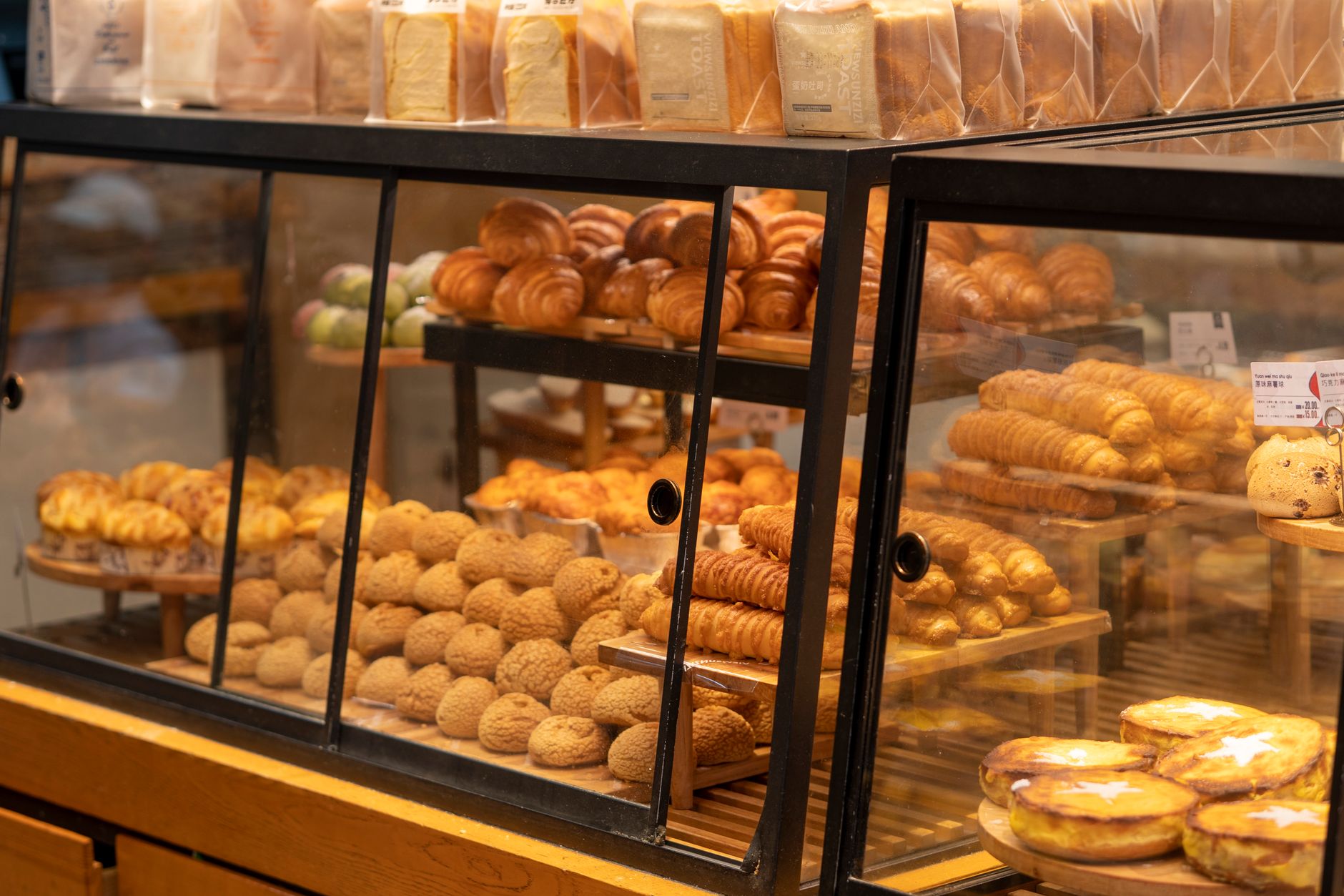 A display case filled with assorted pastries and breads in a bakery setting.
