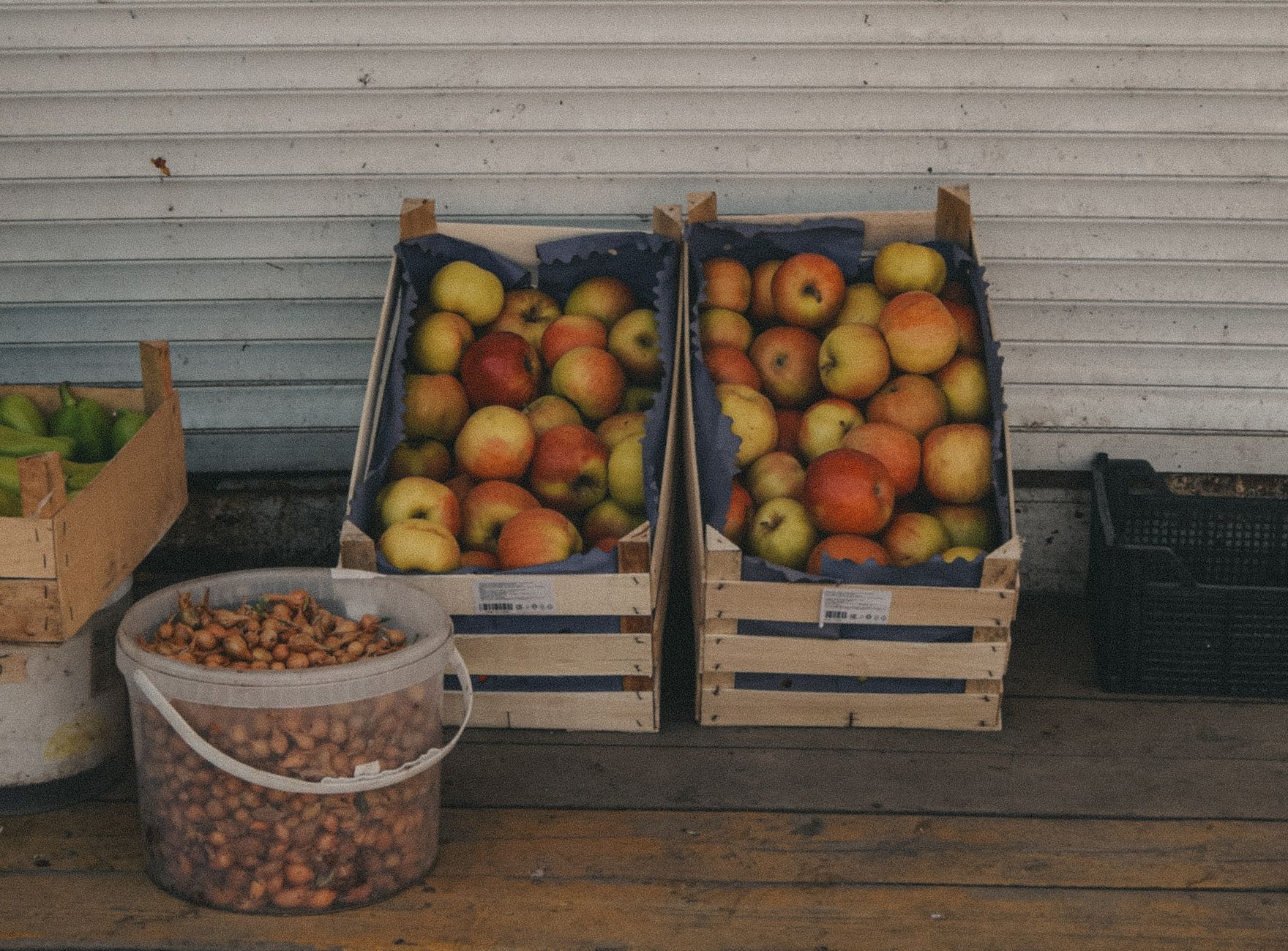 Crates of fresh apples and onions displayed at an outdoor market stall.