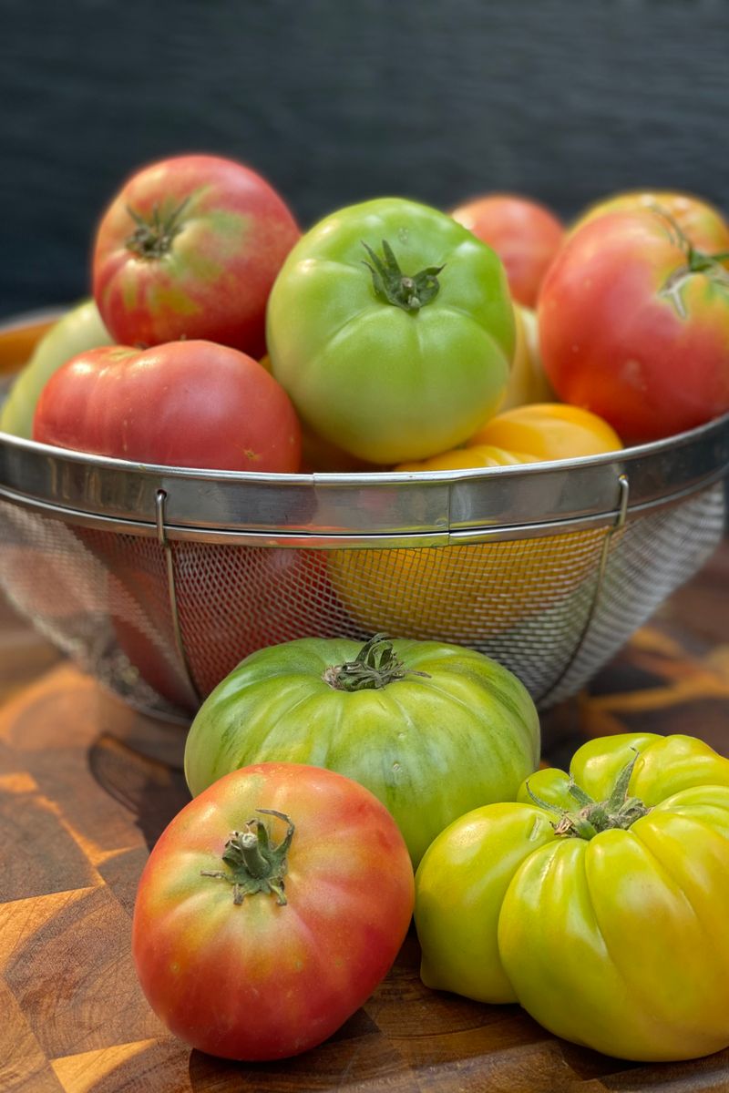 Colorful assortment of fresh heirloom tomatoes on a wooden surface.
